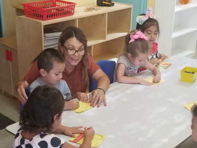 daycare teacher helping children with number recognition in preschool