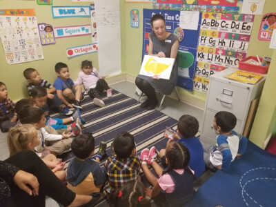 teacher at daycare reading book to group of preschoolers
