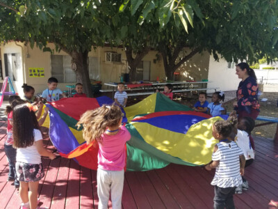 group of preschoolers playing with a parachute on the playground